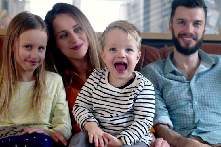 Two young children sat with adults smiling.
