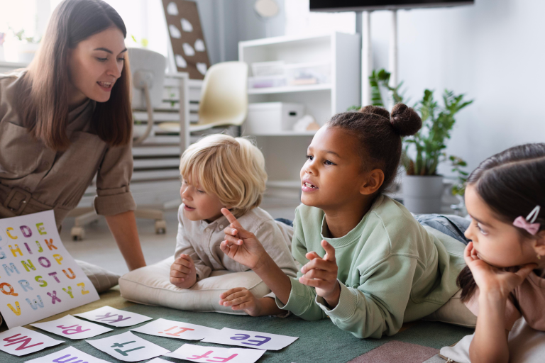Three children learning the alphabet with a teacher
