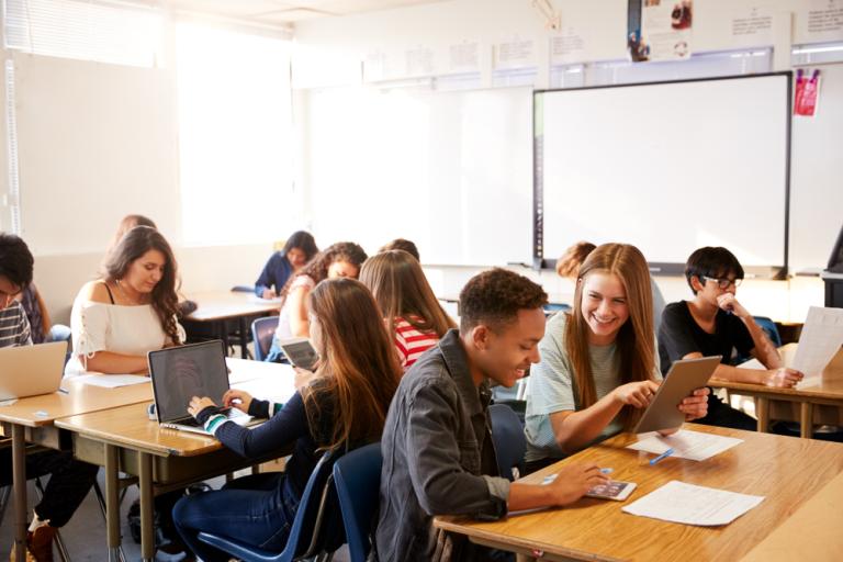 Classroom of students sitting at desks working with laptops 