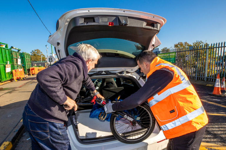 A resident and recycling centre employee unload a car full of household items to be recycled.