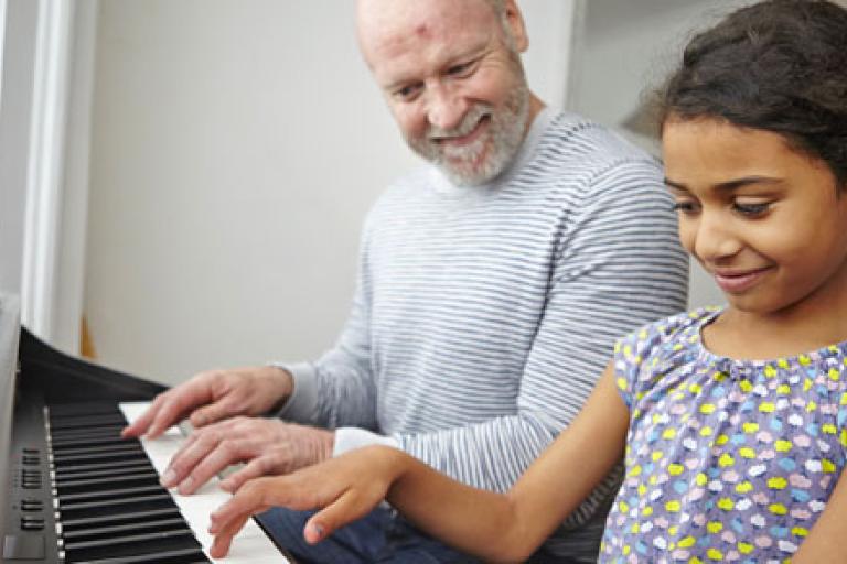 man with girl child playing piano