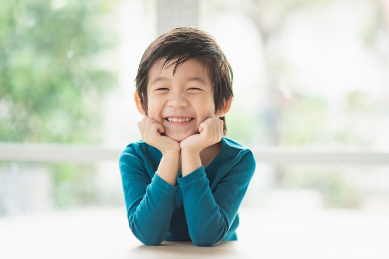 smiling asian boy child sitting at table