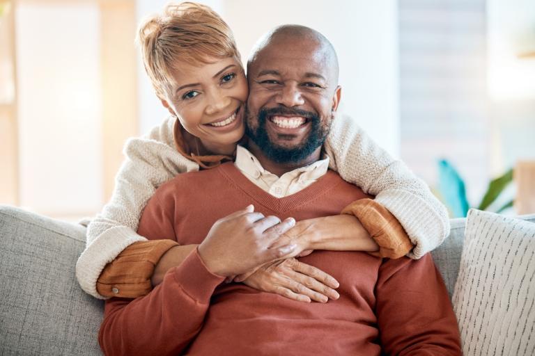 happy smiling black couple with arms clasped around each other
