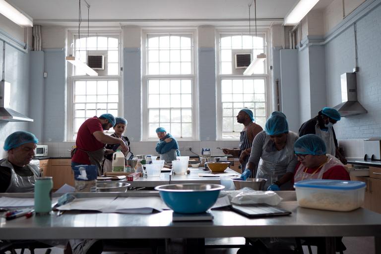 A groups of students are taught cooking skills by tutors in an ACL kitchen.