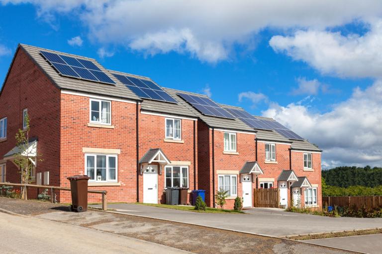 Row of red brick english houses with solar panels on the roof.