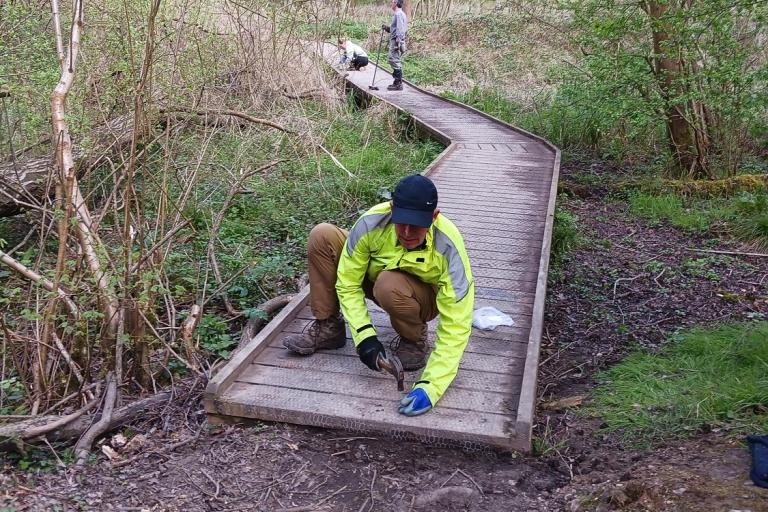 Volunteer repairing boardwalk in the woods