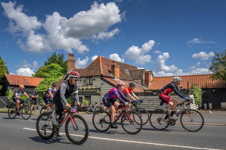 Cyclists riding past an Essex pub during Ford RideLondon 2024