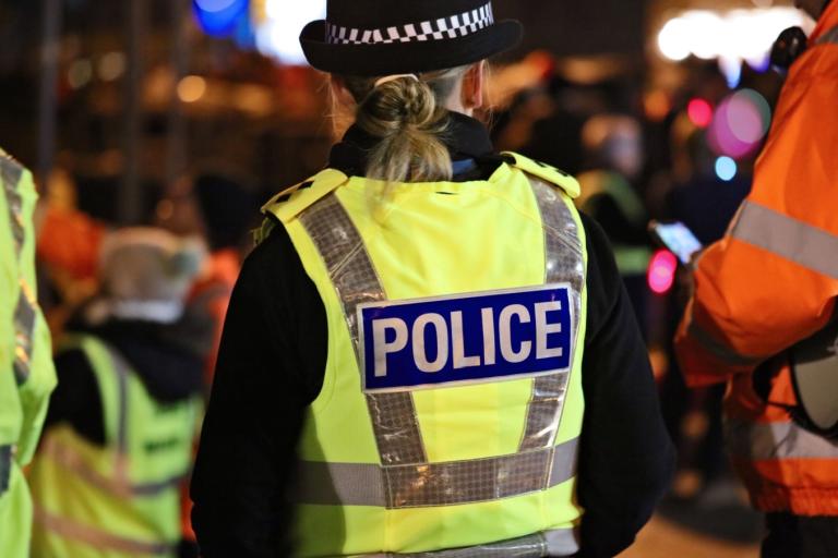 A photograph of a police officer in a high-visibility jacket.