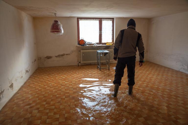 A man wades through a flooded and damaged house