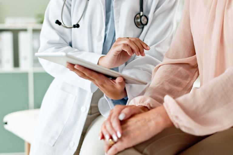 A doctor showing something on a clipboard to a patient. 