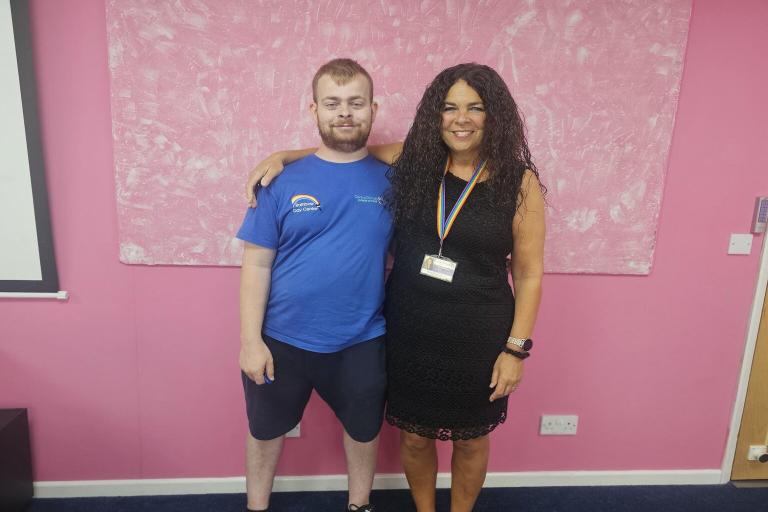 A photograph of a month and son. They are standing next to each other and smiling.