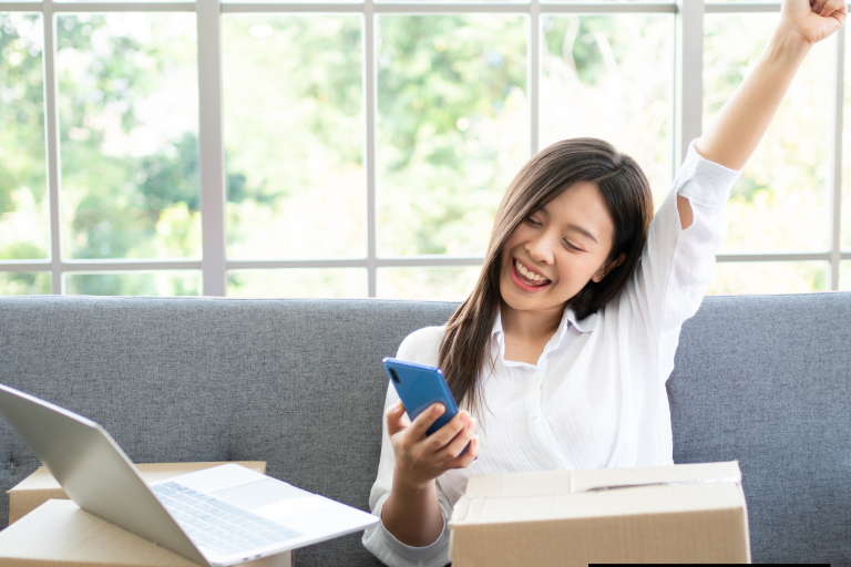 Young female entrepreneur smiling while looking at her phone.