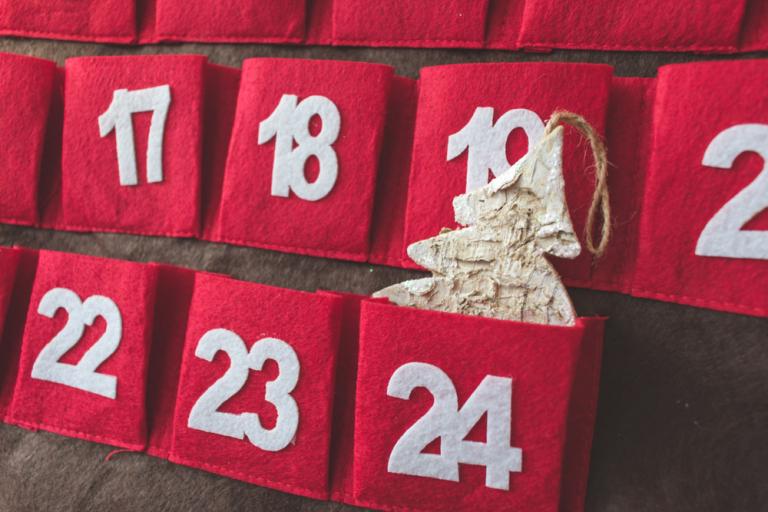 Close up of a red Advent calendar with a christmas tree ornament in the 24th pocket