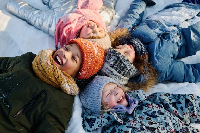 Children playing in the snow, wearing woolly hats and scarves