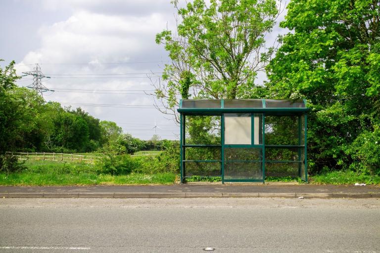 Empty bus stop on the side of a road in the countryside.