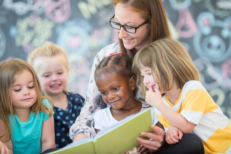 Children reading a story with a woman